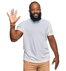 Young african american man wearing casual white tshirt showing and pointing up with fingers number five while smiling confident and happy.