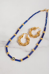 Set of jewelry made of blue glass beads. Necklace and earrings on marble background