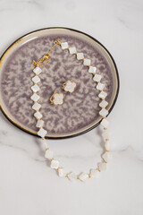 Set of jewelry made of mother of pearl. Necklace and earrings on marble background