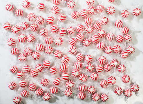 Round peppermint candies on white marble surface
