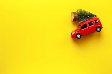 Deurstickers Red toy car with Christmas tree on the roof. Festive New Year concept © 9dreamstudio
