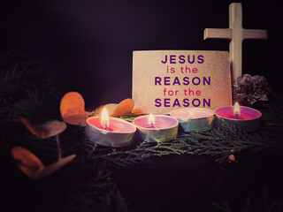 Jesus is the reason for the season on paper. Greating card with candles background. Christmas preparation or Advent season concept. 