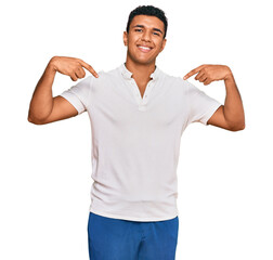 Young arab man wearing casual clothes looking confident with smile on face, pointing oneself with fingers proud and happy.