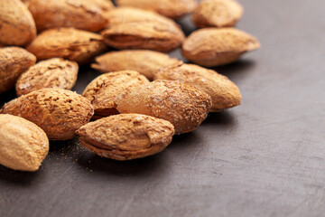 Delicacy roasted almond nuts with nutshell crack on a brown board.