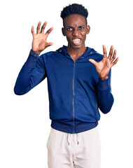 Fototapeta premium Young african american man wearing sportswear smiling funny doing claw gesture as cat, aggressive and sexy expression