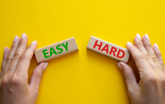 Easy or Hard symbol. Concept word Easy or Hard on wooden blocks. Businessman hand. Beautiful yellow background. Business and Easy or Hard concept. Copy space