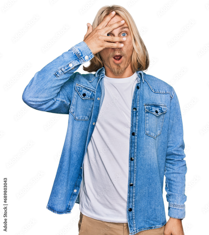 Sticker caucasian man with blond long hair wearing casual denim jacket peeking in shock covering face and ey