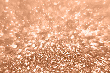 Bright abstract shimmering backdrop in peach fuzz trendy color. Light blurred. Defocused pattern.