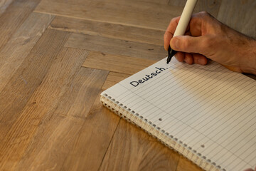 Blank notepad in class on wooden desk for student learning German written language. Deutsch subject for adult learning with handwritten notes and writing exercises for personal development