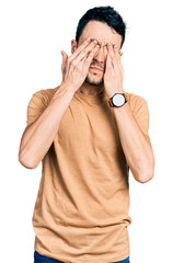 Hispanic man with beard wearing casual t shirt rubbing eyes for fatigue and headache, sleepy and...