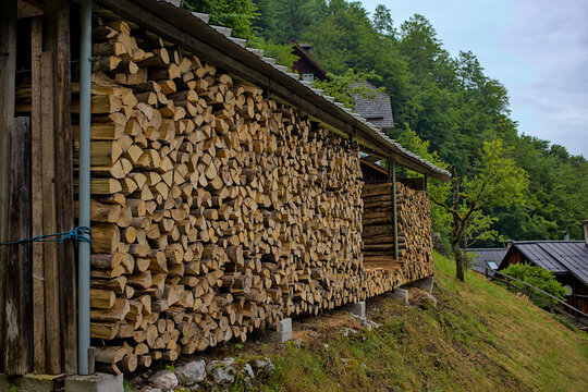 Hallstatt, Austria. Wood stack with stacked firewood stock for winter heating. A pile of stacked firewood under the roof, prepared for heating the house. Firewood stored for heating in winter.