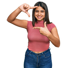 Young hispanic girl wearing casual t shirt smiling making frame with hands and fingers with happy face. creativity and photography concept.