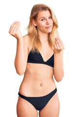Young beautiful blonde woman wearing bikini doing money gesture with hands, asking for salary...