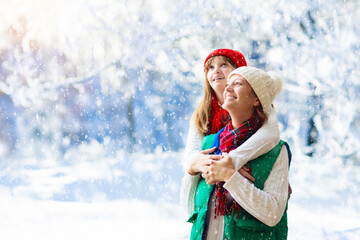 Mother and child in knitted winter hats in snow.