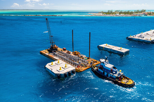 Fototapeta Aerial View of pier construction in the Bahamas. The tug boat, Miss Ashley, supports a barge and crane alongside the pier, Berry Islands, The Bahamas.