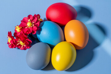 Colorful eggs, symbolizing Easter, on a colorful background and flowers