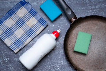 A frying pan next to a sponge and dishwashing liquid. Flat lay photo showing washing dishes