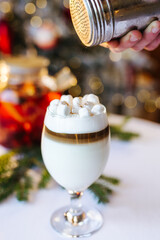 Christmas drink coffee latte with cinnamon and marshmallows on the table near the Christmas tree