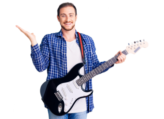 Young handsome caucasian man playing electric guitar celebrating victory with happy smile and winner expression with raised hands