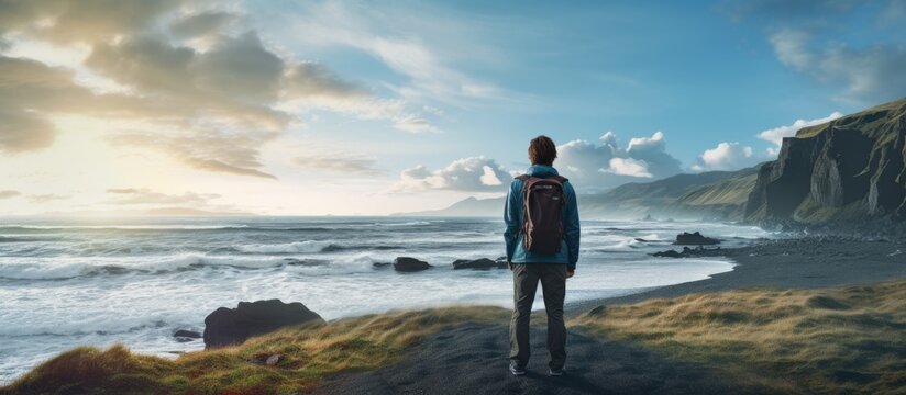 A sportsman is watching ocean waves in nature A man is standing on the ocean beach and watching waves in the wild nature of Iceland. Copyspace image. Square banner. Header for website template