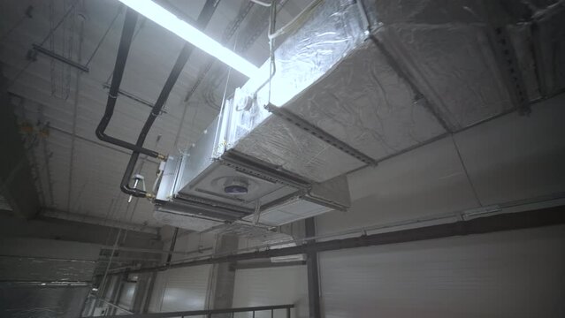 HVAC Duct Cleaning, Ventilation pipes in silver insulation material hanging from the ceiling inside new building.