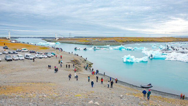 Glacier Lagoon Jokulsarlon, Iceland. Bridge, icebergs and tourists at sunset. Touristic activity in Glacier Lagoon at summer