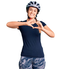 Beautiful caucasian woman wearing bike helmet smiling in love doing heart symbol shape with hands. romantic concept.