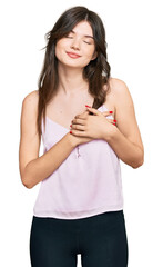 Young beautiful caucasian girl wearing casual clothes smiling with hands on chest with closed eyes and grateful gesture on face. health concept.