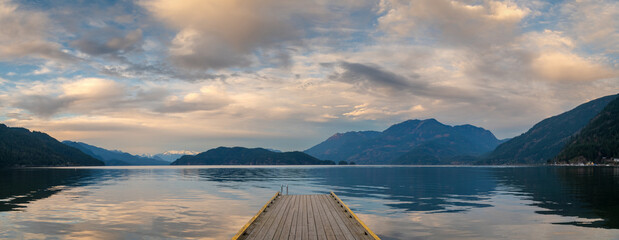 Sunset with Long Pier Leading Out into Water.  Harrison Lake, BC, Canada area is breathtaking with beautiful coves, beaches and islands, waterfalls, coniferous forests and snow-capped mountains.