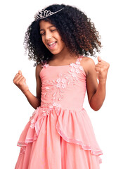 African american child with curly hair wearing princess crown very happy and excited doing winner gesture with arms raised, smiling and screaming for success. celebration concept. © Krakenimages.com