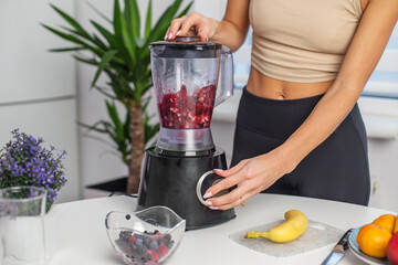 Healthy food concept. Close up of woman prepare to blending berries to make smoothie at home kitchen