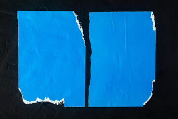 Scraps of two blue posters on a black background.