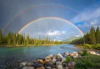 View of a river crossing the Banff National Park with the rainbow in Alberta region of Canada.