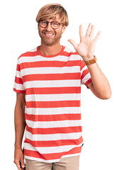 Handsome caucasian man with beard wearing casual clothes and glasses showing and pointing up with fingers number five while smiling confident and happy.