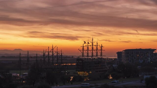 Time-Lapse of Sunrise at the Sea in a Port with Sailing Ships. The Sun Rises Behind the Hills, Painting the Sky in Fiery Bright Colors. Dolly Zoom.