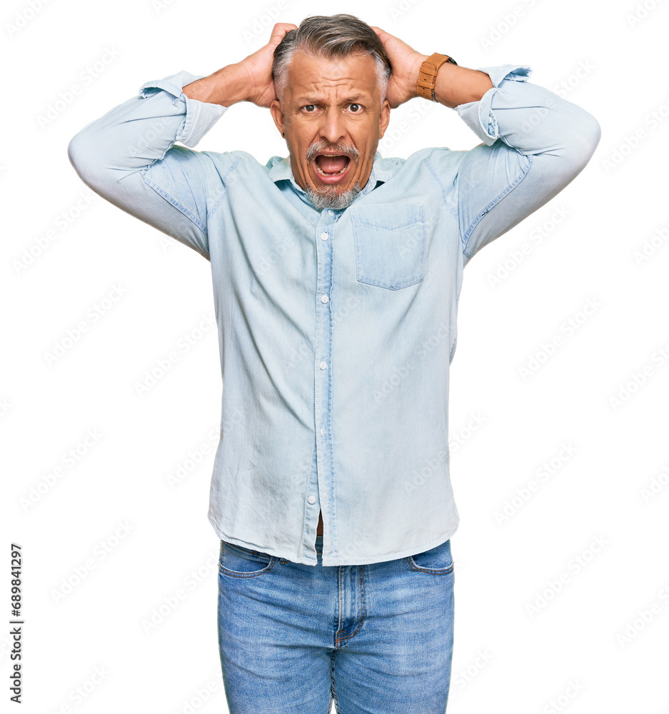 Poster middle age grey-haired man wearing casual clothes crazy and scared with hands on head, afraid and su