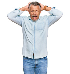 Middle age grey-haired man wearing casual clothes crazy and scared with hands on head, afraid and surprised of shock with open mouth
