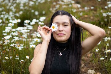 Mujer atractiva cubriendo los ojos con ramas de flores durante la primavera