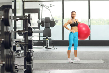Young sporty female standing with an exercise ball at a fitness center