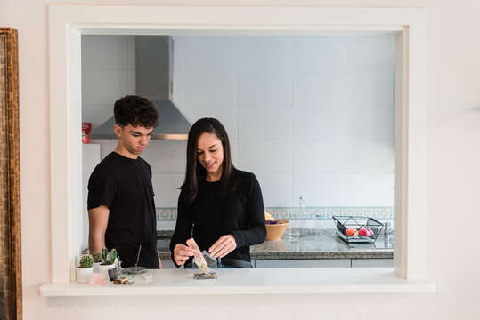 Happy ethnic couple throwing money into house shaped box