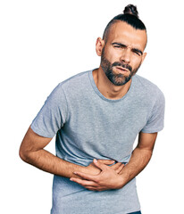Hispanic man with ponytail wearing casual grey t shirt with hand on stomach because nausea, painful...