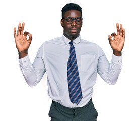Handsome business black man wearing white shirt and tie relax and smiling with eyes closed doing meditation gesture with fingers. yoga concept.
