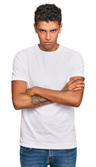 Young handsome african american man wearing casual white tshirt skeptic and nervous, disapproving expression on face with crossed arms. negative person.