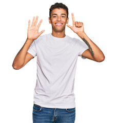 Young handsome african american man wearing casual white tshirt showing and pointing up with fingers number seven while smiling confident and happy.