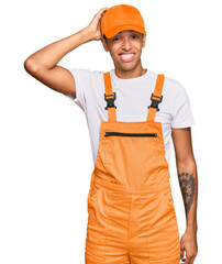 Young handsome african american man wearing handyman uniform confuse and wonder about question. uncertain with doubt, thinking with hand on head. pensive concept.