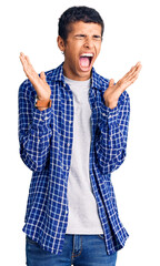 Naklejka premium Young african amercian man wearing casual clothes celebrating mad and crazy for success with arms raised and closed eyes screaming excited. winner concept
