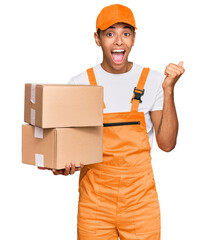 Young handsome african american man holding delivery package screaming proud, celebrating victory and success very excited with raised arms