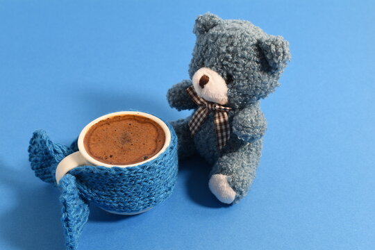 Coffee cup dressed up with knitted liner and teady bear. Blue Monday concept.