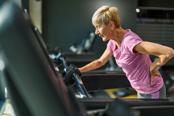 gym sport fitness exercising training mature senior edlerky woman running cardio treadmill tired...