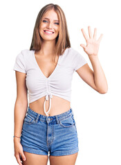 Young beautiful blonde woman wearing casual white tshirt showing and pointing up with fingers number five while smiling confident and happy.